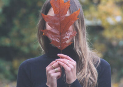 Fille avec une feuille devant, balade à faire en automne